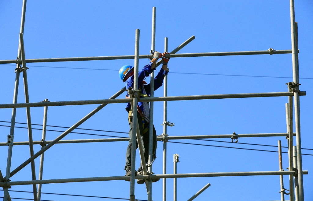 A worker balances on steel frames as the construction of the skyway pushes through at a major thoroughfare in metro Manila